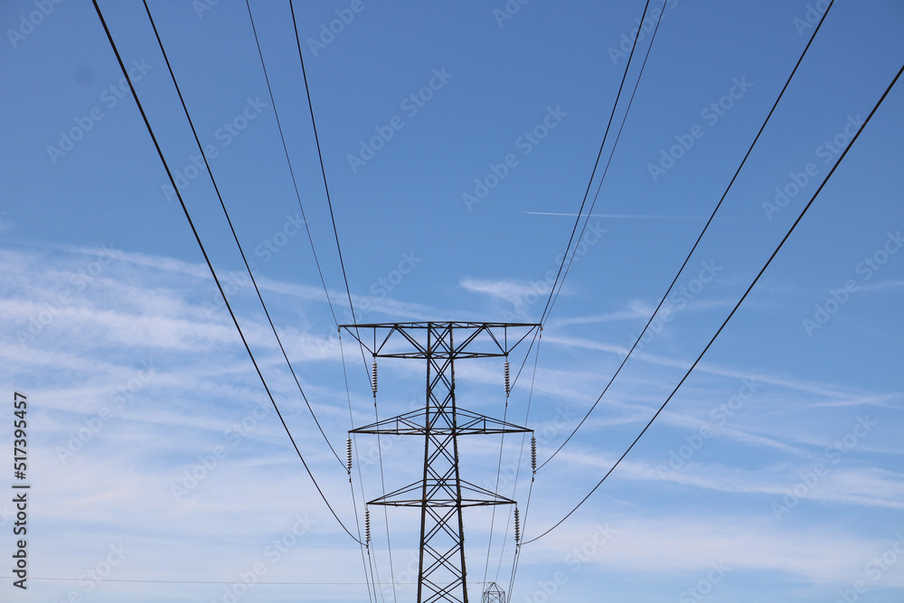 Electricity pylon against blue wispy cloudy sky with space for copy