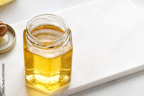 Opened Glass jar of honey with metal lid on table on a white background. Superfood, alternative sugar substitute.