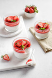 Panna cotta with strawberry in a glass jars decorated with fresh berries and mint, Traditional Italian sweet dessert. Strawberry creamy dessert - panna cotta.