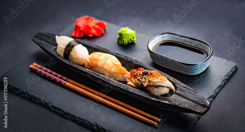 Sushi sashimi set with shrimps, ginger and soy sauce served with chopsticks and wasabi on black table. Traditional japanese meal with rice and seafood