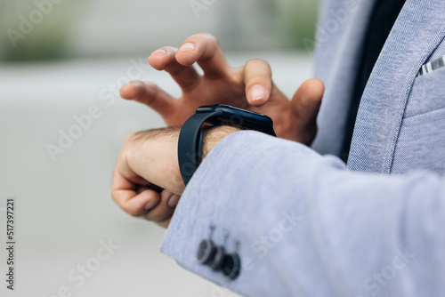 Closeup shot of male's hand uses of wearable smart watch at outdoor. Smartwatch on a business man's hand outdoor. Gorgeous businessman touching a smart watch. Smart watch