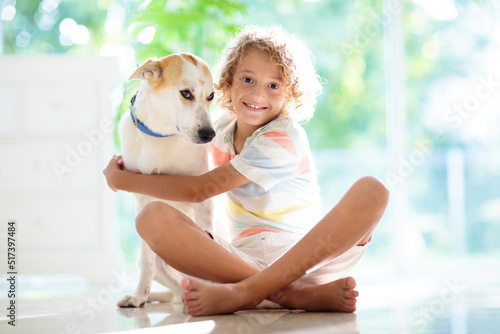 Child playing with dog. Kid and puppy at home.