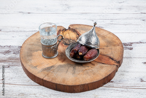 Dates or dates palm fruit (Hurma) is a healthy snack. Him Organic Medjool Ready-to-Eat Dates. Ramadan concept: Dates, zam zam water in copper jugs and glasses and on white table. photo