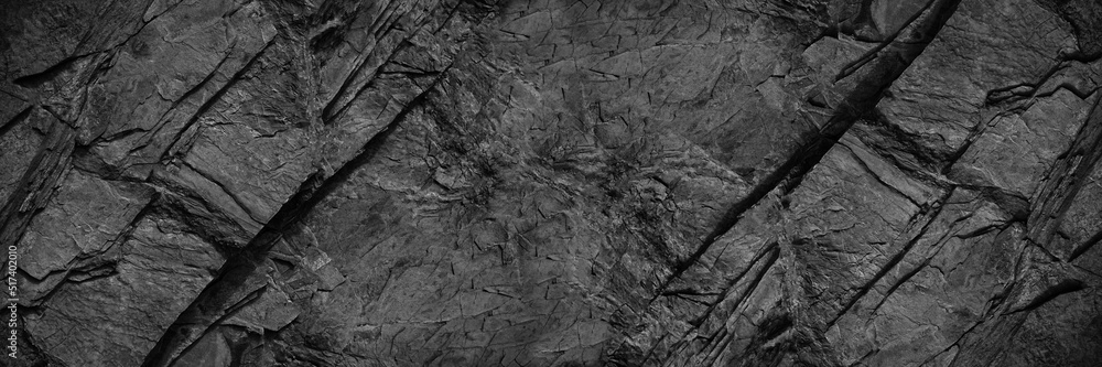 Black rock texture. Rough mountain surface with cracks. Close-up. Granite stone background with space for design. Web banner. Wide. Panoramic. Dark grey. - obrazy, fototapety, plakaty 