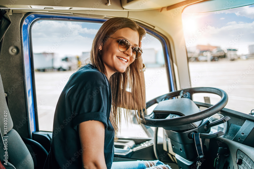 Portrait of beautiful young woman professional truck driver sitting in ...