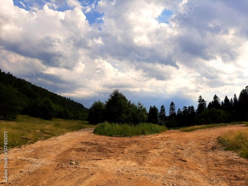 Landscape with gravel road, forest and clouds on mountain Bjelasnica, Bosnia and Herzegovina