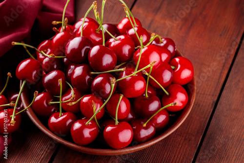 Wallpaper Mural Fresh red cherries in a clay plate on a red napkin. Ripe cherries on a wooden boards. Healthy diet food concept. Close-up Torontodigital.ca