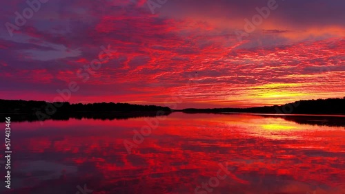 Amazing red sky mirrored in still waters at dawn, dynamic moving perspective.
