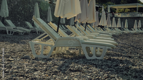 White plastic chaise-longues on the pebble beach