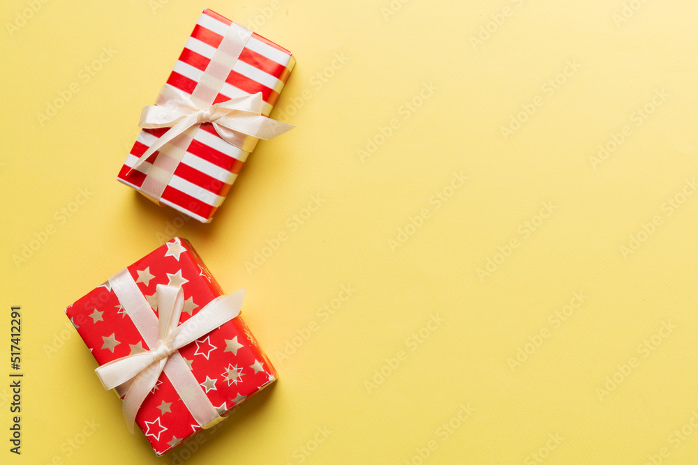 Holiday flat lay with gift boxes wrapped in colorful paper and tied decorated with confetti on colored background. Christmas, Birthday, Valentine and sale concept, top view