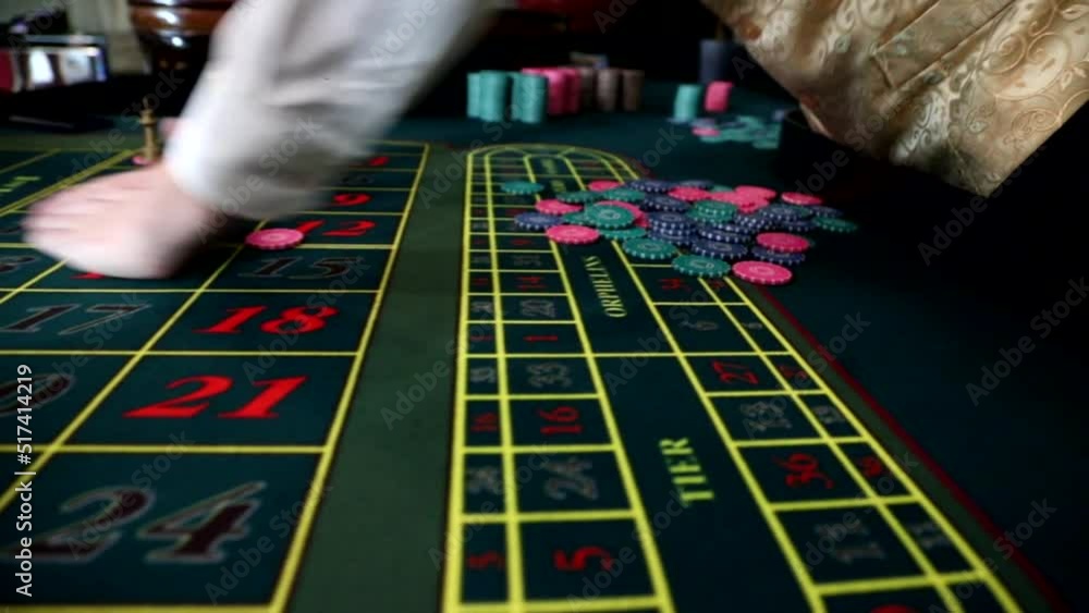 A male croupier collects chips laid out on a roulette table. hands close up. Slow motion A male croupier collects chips laid out on a roulette table. hands close up. Slow motion