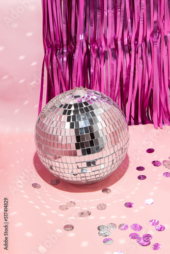 Shiny disco ball, courtain and confetti on pastel light pink background. Trendy party symbols concept. Minimalistic celebration composition.