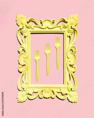 Yellow forks in frame on light pastel pink background. Creative food concept. Minimalistic food composition.