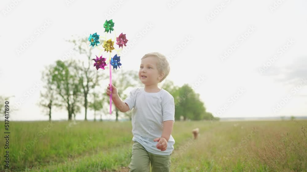 baby boy playing with spinner toy in the park. happy family kid dream lifestyle concept. baby a son plays with a toy windmill outdoors in the forest in summer baby boy playing with spinner toy in the park. happy family kid dream lifestyle concept. baby a son plays with a toy windmill outdoors in the forest in summer