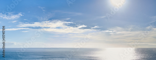 Copy space at sea with the sun in a clear blue sky in the background. Calm ocean tide in an open ocean. A scenic seascape for a relaxing summer holiday with cloudy sky and clean water on the coast