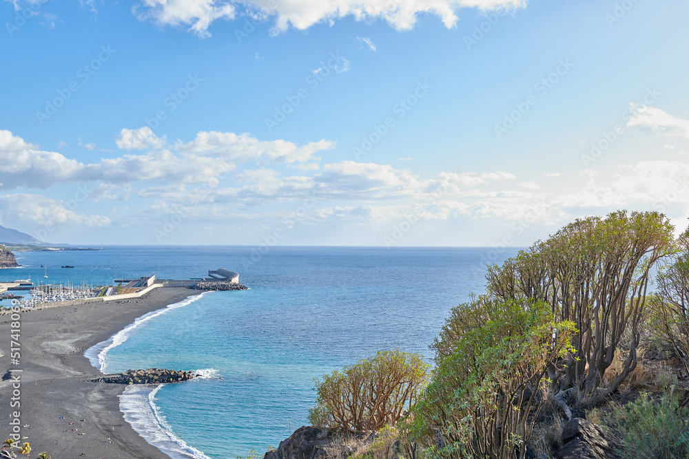 Scenic seaside and seascape of touristic coastal city of Puerto de Tazacorte in La Palma, Spain during summer. Landscape view of a sea with a black sand beach, a blue sky with clouds and copy space.