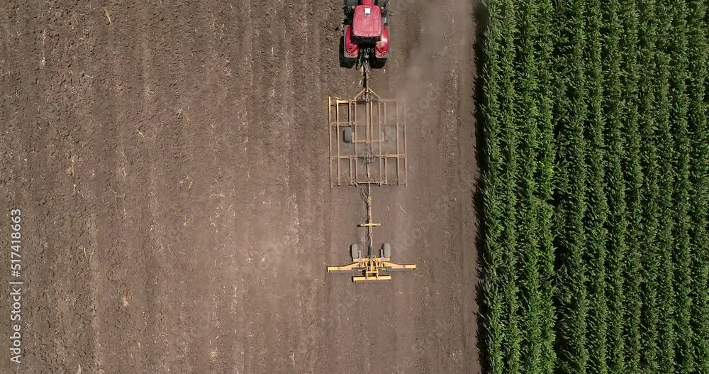Red tractor flattening a field for seeding, Drone follow footage.
Red tractor flattening a field for seeding, Drone follow footage.