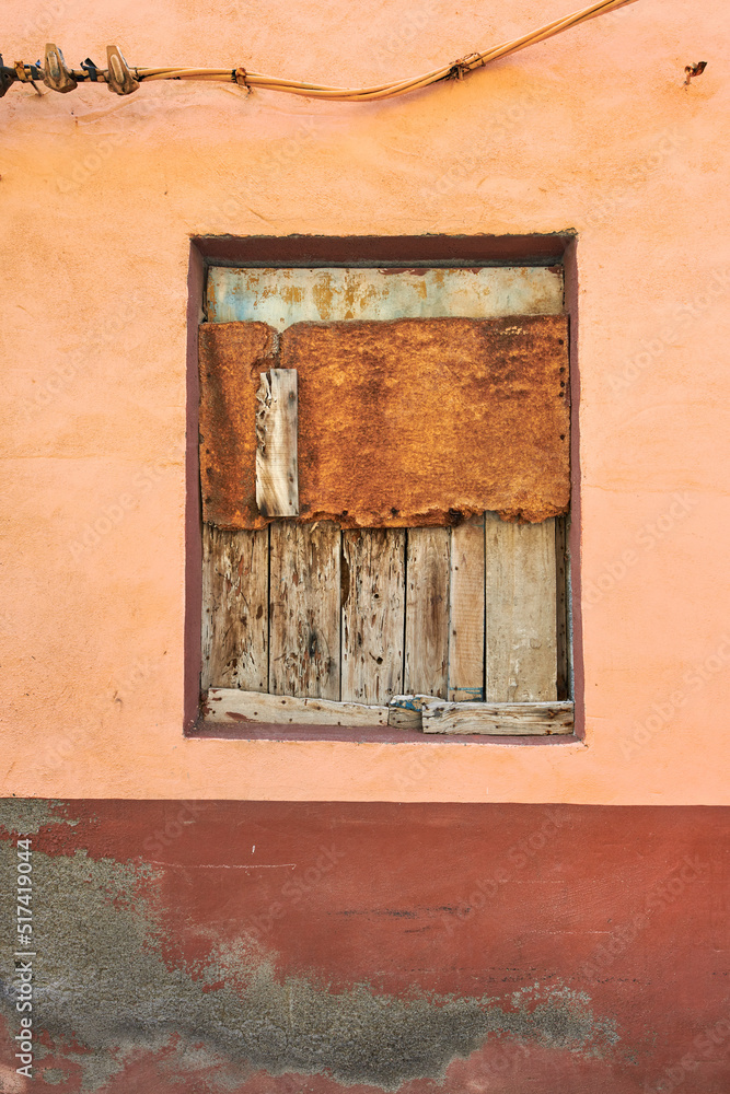 Abandoned and bordered window on an empty house from poverty and economic crisis in Santa Cruz, La Palma, Spain. Wooden boards covering and blocking an old village home with damp mold on the walls Abandoned and bordered window on an empty house from poverty and economic crisis in Santa Cruz, La Palma, Spain. Wooden boards covering and blocking an old village home with damp mold on the walls