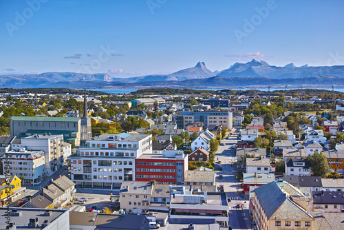 Aerial view of Bodo city in Norway on a sunny day with a blue sky. Scenic modern urban landscape of streets and buildings near a mountain horizon with copy space. Peaceful rural town from above photo