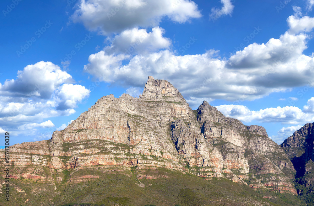 Landscape of mountains on a blue cloudy sky. Beautiful view of mountain outcrops with hill covered in green grass, shrubs and bushes on popular landmark or hiking location in Cape Town, South Africa
