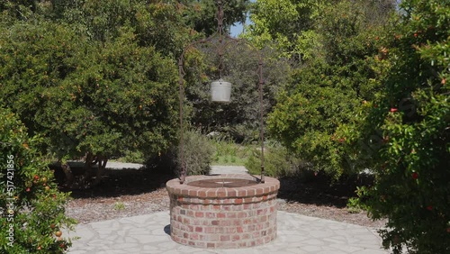 This video shows a wishing well in the center of a garden. photo