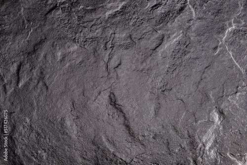 Dark gray background from natural slate. Texture of stone closeup. Graphite background macro