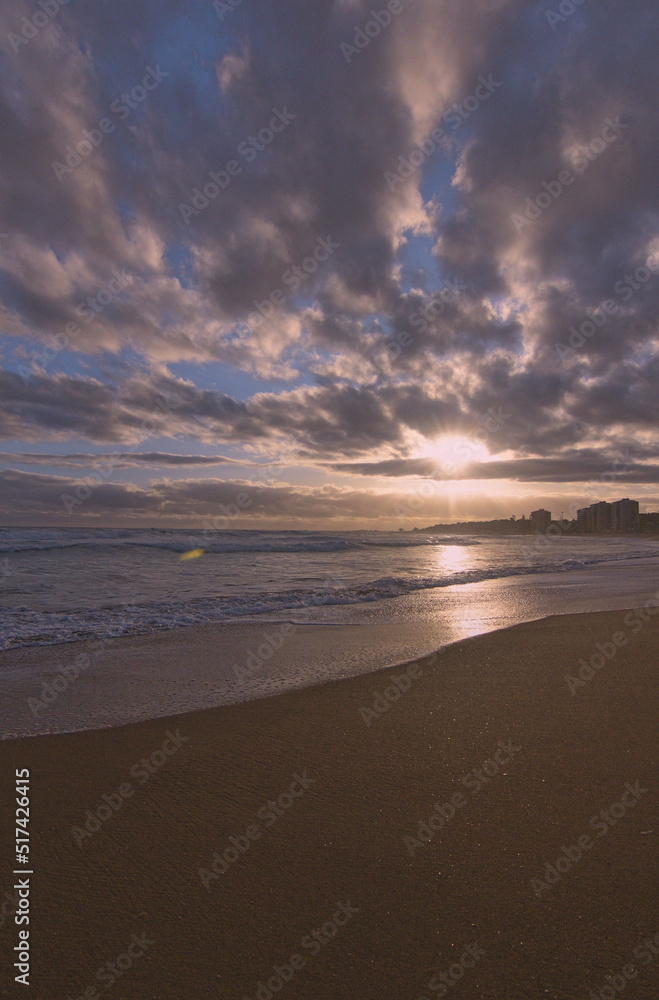 puesta de sol contra el sol en la playa con nubes en el horizonte
