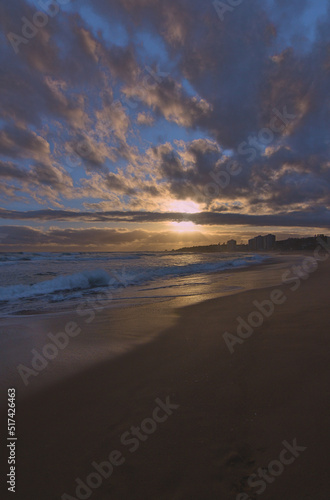 puesta de sol contra el sol en la playa con nubes en el horizonte