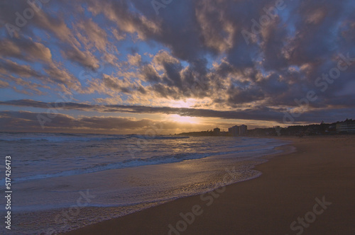 Fototapeta Naklejka Na Ścianę i Meble -  puesta de sol contra el sol en la playa con nubes en el horizonte