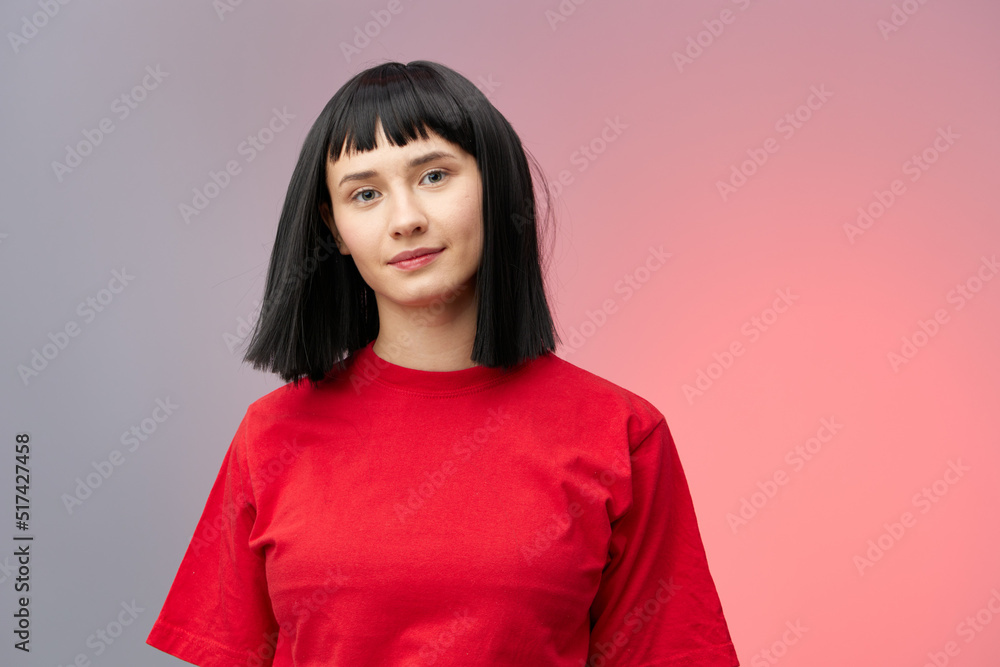 horizontal photo of a cute, beautiful woman with short black hair looking pleasantly into the camera standing on a gray background with red lighting in a red T-shirt horizontal photo of a cute, beautiful woman with short black hair looking pleasantly into the camera standing on a gray background with red lighting in a red T-shirt