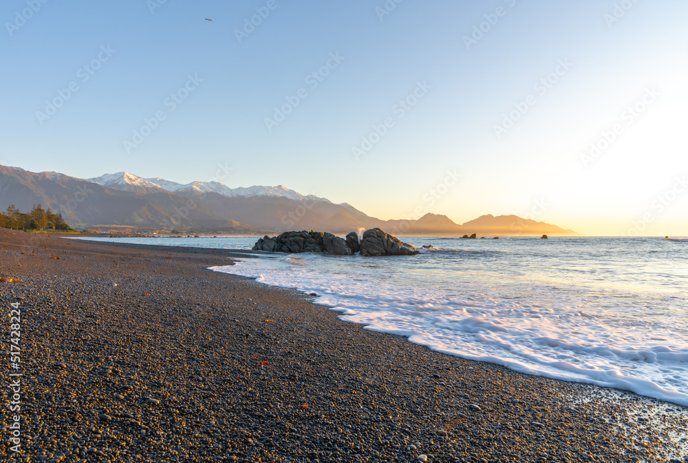 View along Kaikoura main beach to sunrise where horizon and mountains meet