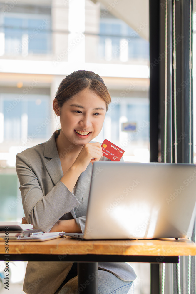 Asian businesswomen enjoy online shopping using a credit card at the coffee shop. with a laptop on the table Asian businesswomen enjoy online shopping using a credit card at the coffee shop. with a laptop on the table
