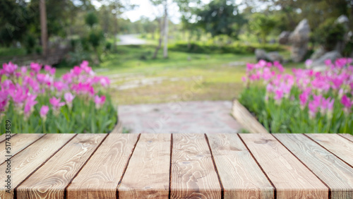 Empty wood table top and blurred flower tree in garden background - can used for display or montage your products.