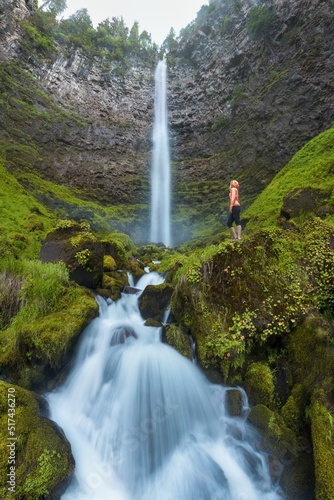 A woman standing on the rock at Beautiful falls in forest  West coast USA. Watson Falls is waterfall on Watson Creek  a tributary of the Clearwater River  in Douglas County in the U.S. state 