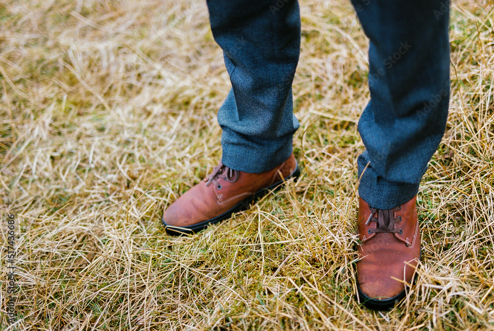 Men feet in brown shoes on dry grass. Close-up