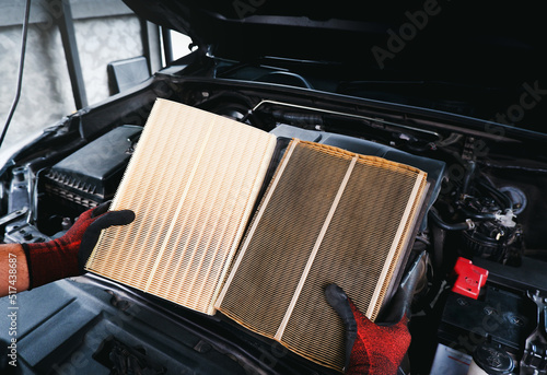 Fotografi Auto mechanic compares a clean new air filter to an old, filthy one with a engin