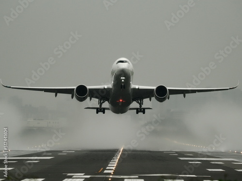 雨の日に水煙を上げて離陸する旅客機