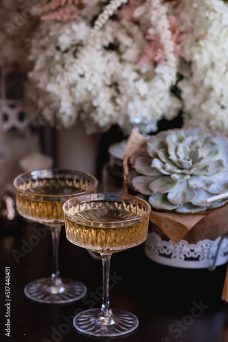 A bouquet of white hydrangeas and pink astilba, succulent, candles and a fashionable glass for dessert and champagne with wine inside. Cozy interior. The concept of a party, wedding and holiday.