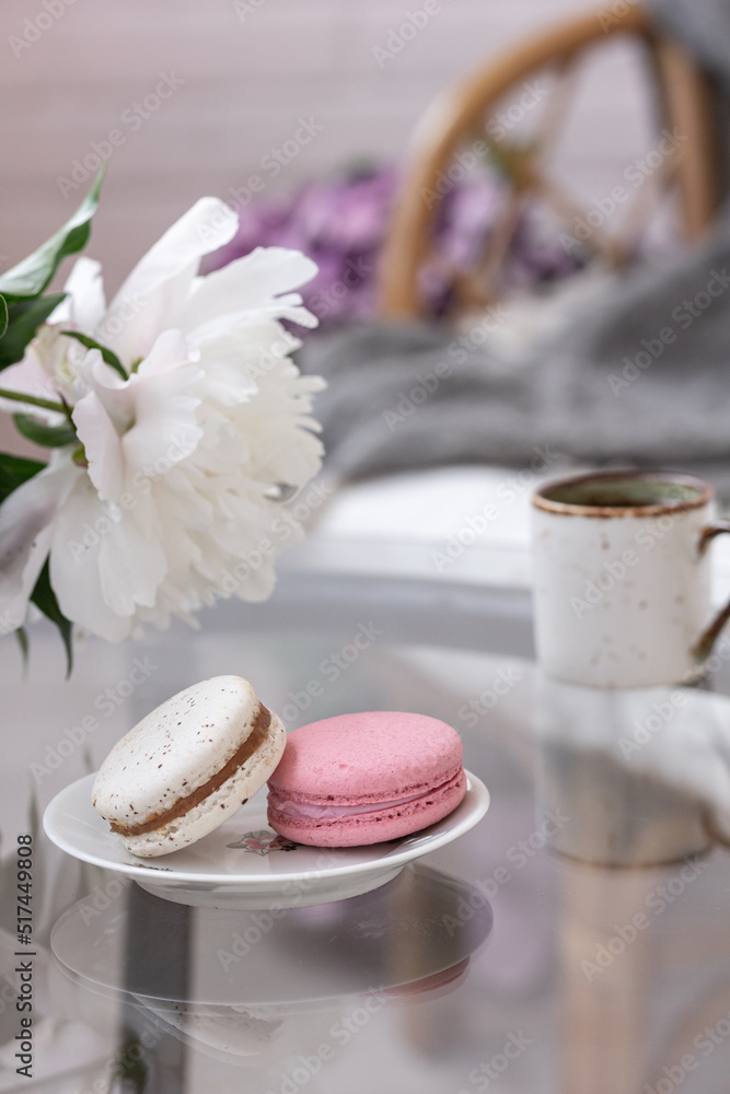 Summer vibes – summer dessert on a glass table, macarons, cup of coffee or tea , white flower, stylish rattan sofa, soft pillows, plaid. Elegant accessories in modern decor Copy space Summer vibes – summer dessert on a glass table, macarons, cup of coffee or tea , white flower, stylish rattan sofa, soft pillows, plaid. Elegant accessories in modern decor Copy space