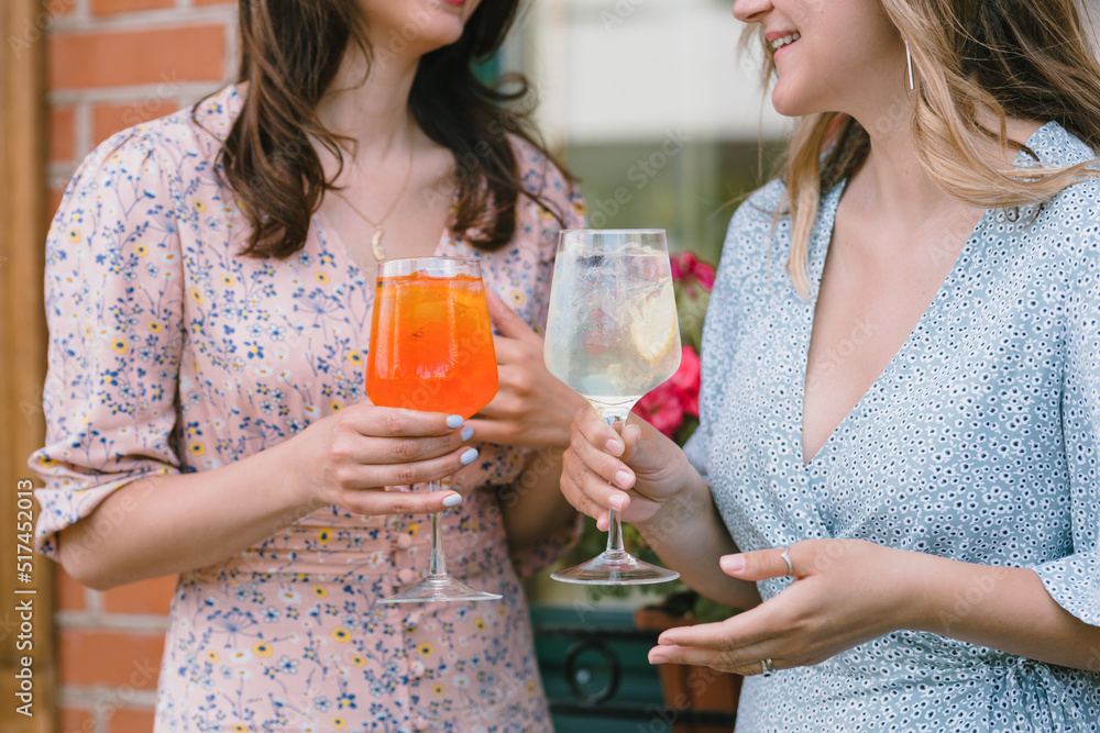 Close up of happy women drinking cocktails outdoors on sunny day. Limoncello tonic and aperol cocktails. Close up of happy women drinking cocktails outdoors on sunny day. Limoncello tonic and aperol cocktails.