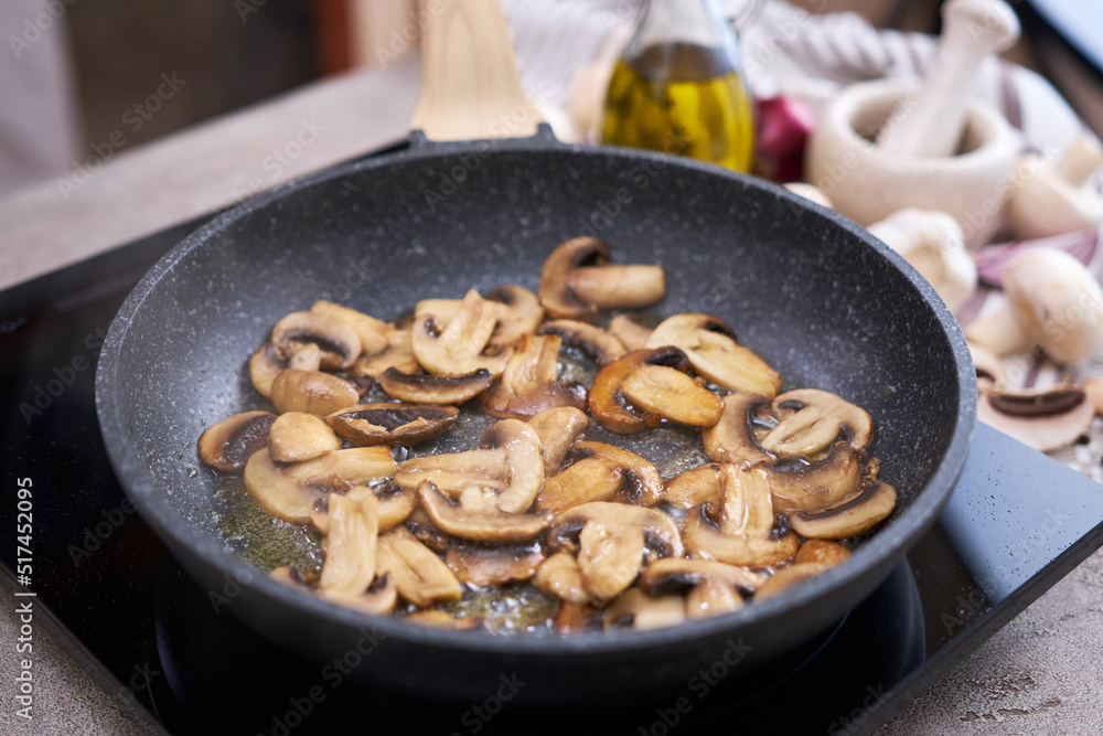 Sliced mushrooms in a frying pan on induction hob at domestic kitchen Sliced mushrooms in a frying pan on induction hob at domestic kitchen