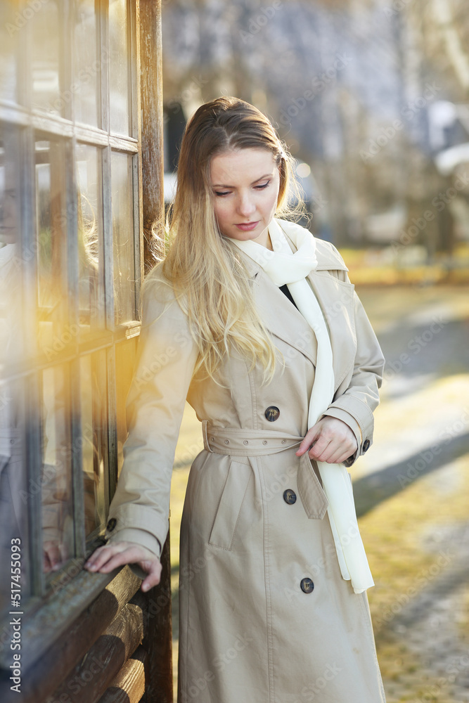 young blond beautiful woman with long hair wearing trench coat closeup street portrait on fall park background young blond beautiful woman with long hair wearing trench coat closeup street portrait on fall park background