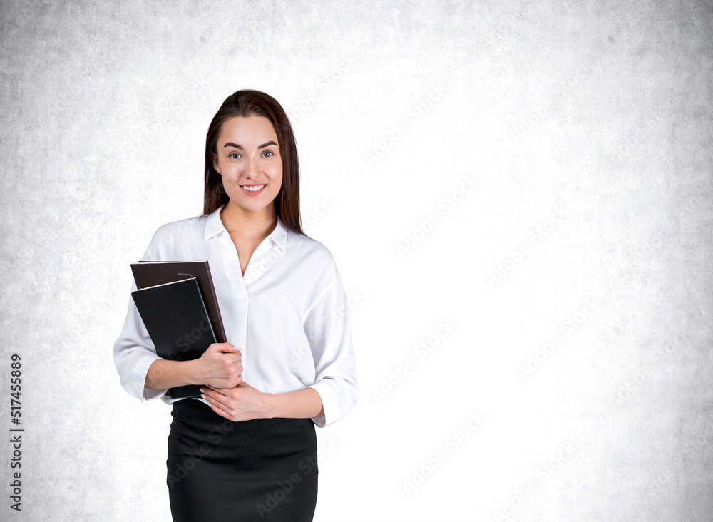 Young businesswoman with notebook, smiling on grey wall background Young businesswoman with notebook, smiling on grey wall background