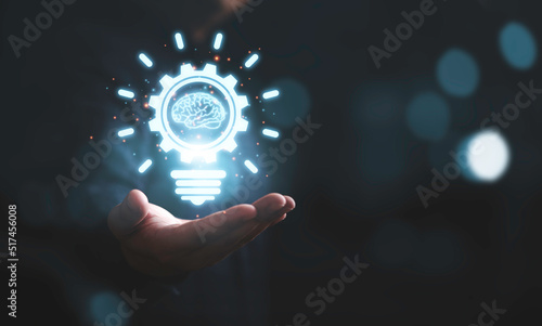 Businessman holding glowing drawing lightbulb with virtual brain and connection line, creative thinking ideas and innovation concept.