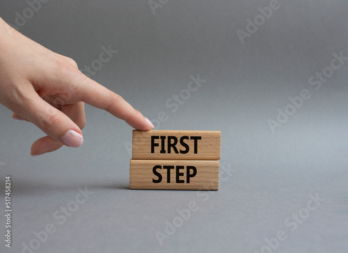 First step symbol. Wooden blocks with words 'First step'. Beautiful grey background. Businessman hand. Business and 'First step' concept. Copy space.