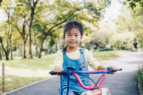 Asian kid girl ride bike in tree park