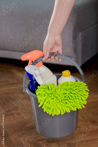 Woman holding a bucket of detergents and a rag. Cleaning at home. Housework. Cleaning products. photo