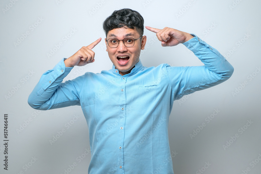 Fototapeta premium Handsome young man wearing casual shirt smiling pointing to head with both hands finger, great idea or thought