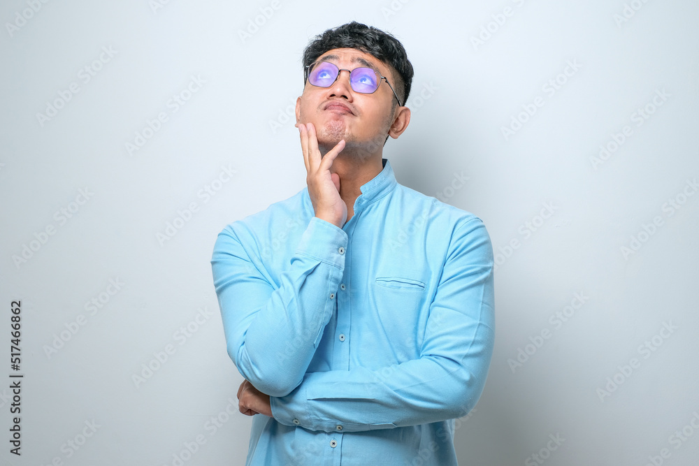Young asian man thinking worried about a question, concerned and nervous with hand on chin Young asian man thinking worried about a question, concerned and nervous with hand on chin