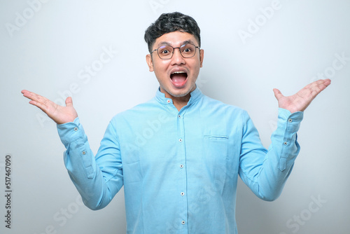 Young asian man celebrating crazy and amazed for success with arms raised and open eyes screaming